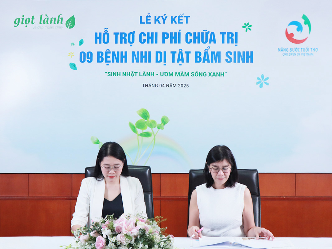 Đại diện Giọt Lành (trái) và đại diện Quỹ Nâng Bước Tuổi thơ (phải) đặt bút ký biên bản tài trợ